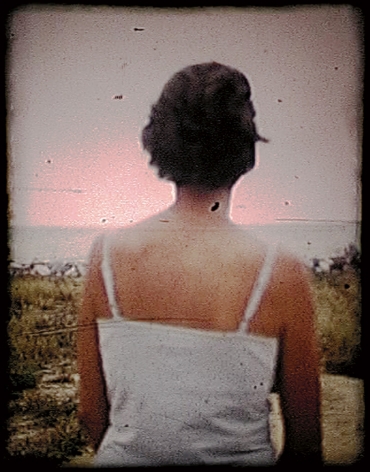 Colby Caldwell  fig (2), [still from The Last Photograph], 2004  Archival pigment print mounted on wood panel with a hand waxed surface  15h x 12w in, color photograph of a woman from behind wearing a white camisole, landscape in the background.
