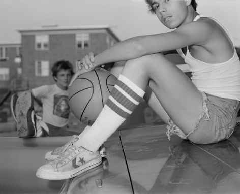 1970s black and white photograph of boy on car hood with knee high socks and basketball, by Mike Smith