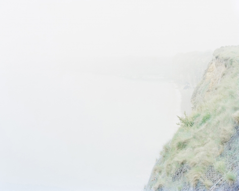 Ponte du Hoc, Artlantic Wall Fortifications (France), 2017  Archival Pigment Print  30 x 37.5 inches  Edition of 5, image of the coastline with wall fortifications and greenery in middle right side of image.