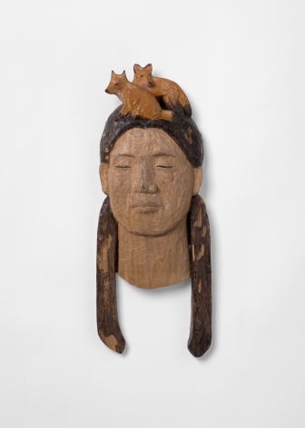 Wooden wall sculpture of head with two small foxes
